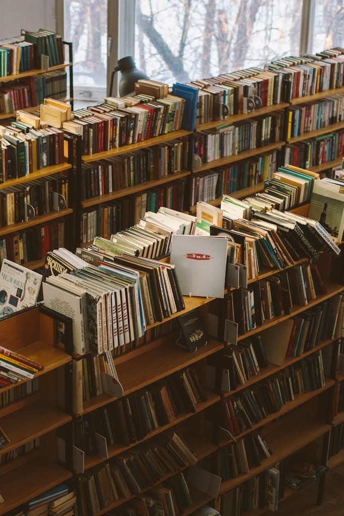 A warm view of a cozy library filled with rows of bookshelves and a variety of books.